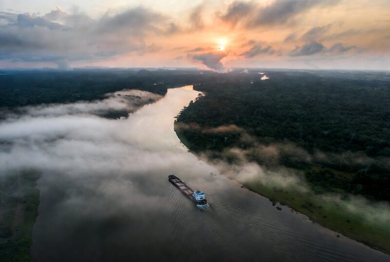 Embarcación de carga navegando un río de la Amazonía al amanecer